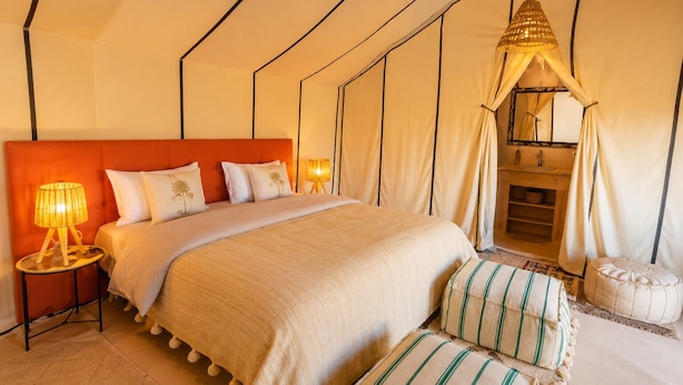 Amplia habitación tipo tienda con una cama grande, una lámpara de noche y un dosel sobre la cama.