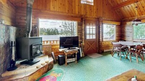 Ein Holzblockhaus-Interieur mit Kamin, Fernseher und Essbereich.