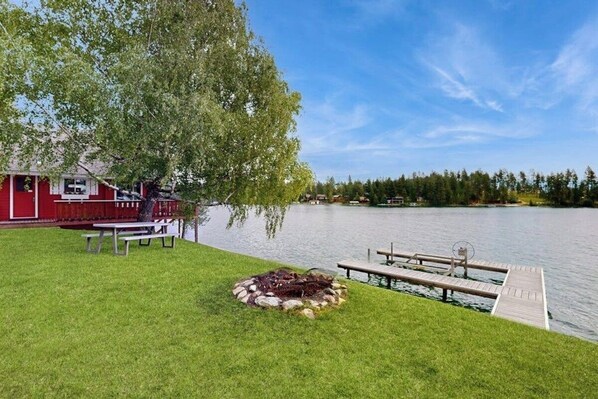 A lakeside property with a red building, a dock, and a fire pit.