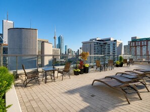 Eine Dachterrasse mit Sitzgelegenheiten, Blumentöpfen und Blick auf eine Stadtlandschaft.