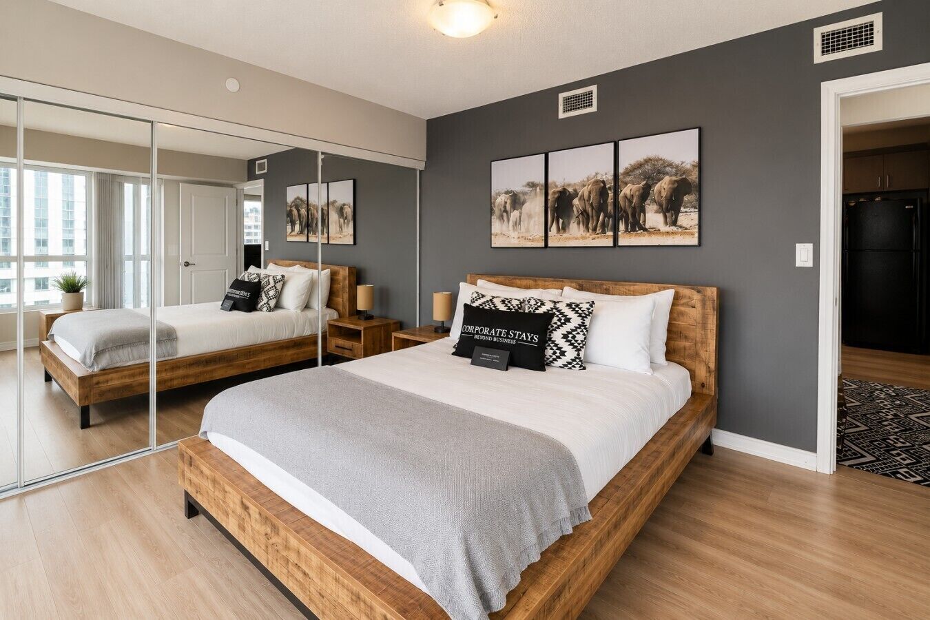 A modern bedroom with a large bed, a mirror, and artwork on the wall.
