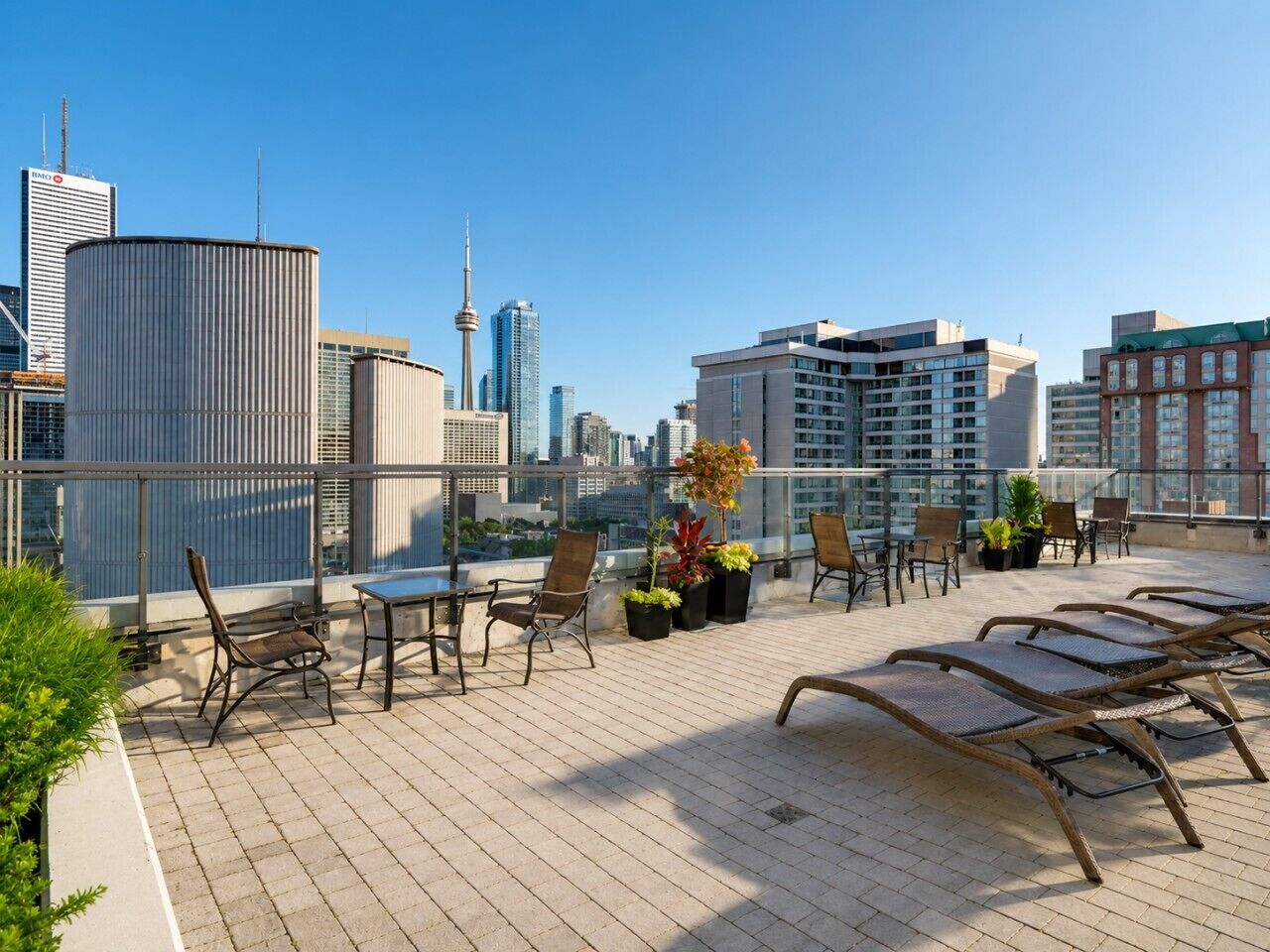 A rooftop terrace with seating, potted plants, and a city skyline view.