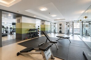 A gym with exercise equipment, a bench, and a rack of dumbbells. - Modern 1BR in Downtown | Gym, WiFi & Workspace (Toronto)