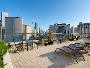 Eine Dachterrasse mit Sitzgelegenheiten, Blumentöpfen und Blick auf eine Stadtlandschaft.