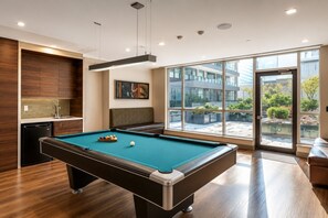 A pool table with balls, a bench, and a view of the outdoors through large windows. - Bright 1BR at Motion | Prime Downtown Location (Toronto)