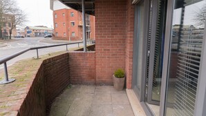 Ein Balkon mit Backsteinmauer, einem Blumentopf und Blick auf eine Straße mit Gebäuden.
