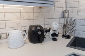 Une cuisine équipée d’une machine à café, d’une bouilloire et d’un bloc à couteaux.