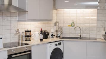 A modern kitchen with a built-in washing machine, stainless steel appliances, and a tiled backsplash.