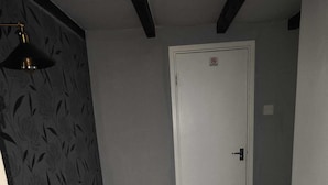 Un pasillo con un papel tapiz decorado, una puerta blanca y suelo alfombrado.