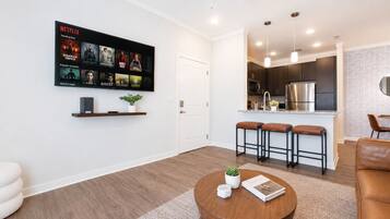 Un salon moderne avec une table basse, une bibliothèque et un téléviseur fixé au mur, diffusant des programmes de Netflix.