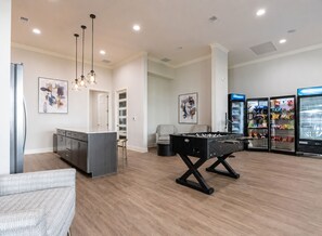 A modern living room with a foosball table, a bar area, and a refrigerator stocked with snacks. - 2BR Suite w/ POOL, PICKLEBALL, GAMES, GYM, COLD PLUNGE, SAUNA, (Elizabethtown)