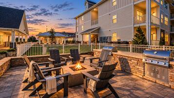 Un espace extérieur aménagé avec une terrasse, un foyer, des sièges et un barbecue.