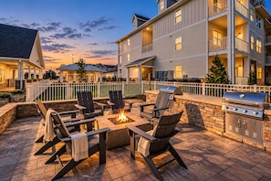 An outdoor patio area with a fire pit, seating, and a grill.