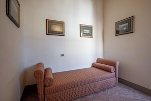 Una habitación con una cama individual, dos cuadros en la pared y un termostato.