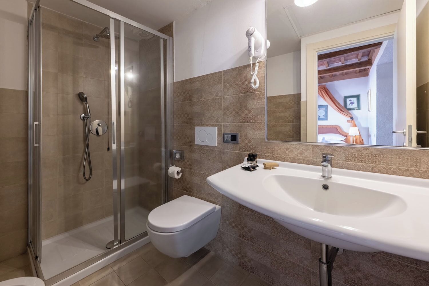 Un baño moderno con ducha de vidrio, lavamanos blanco y un inodoro.