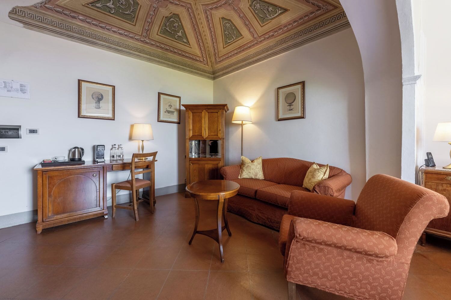 Ein Wohnzimmer mit einer Couch, Sesseln, einem Couchtisch, einem Schrank und einer Lampe.