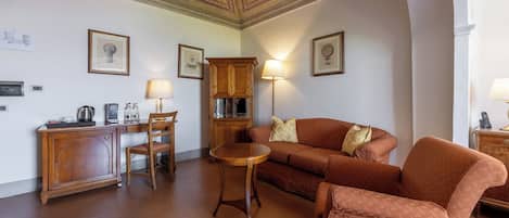 Una sala de estar con un sofá, sillones, una mesa de centro, un mueble y una lámpara.