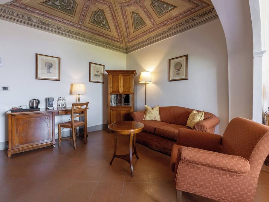 Uma sala de estar com sofá, poltronas, mesa de centro, aparador e luminária.