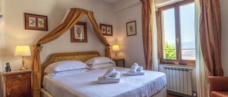 A hotel room with a four-poster bed, a view of the outdoors, and a radiator.