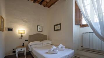 Ein Schlafzimmer mit einem Bett, Nachttisch, Lampe und gerahmten Bildern an der Wand.