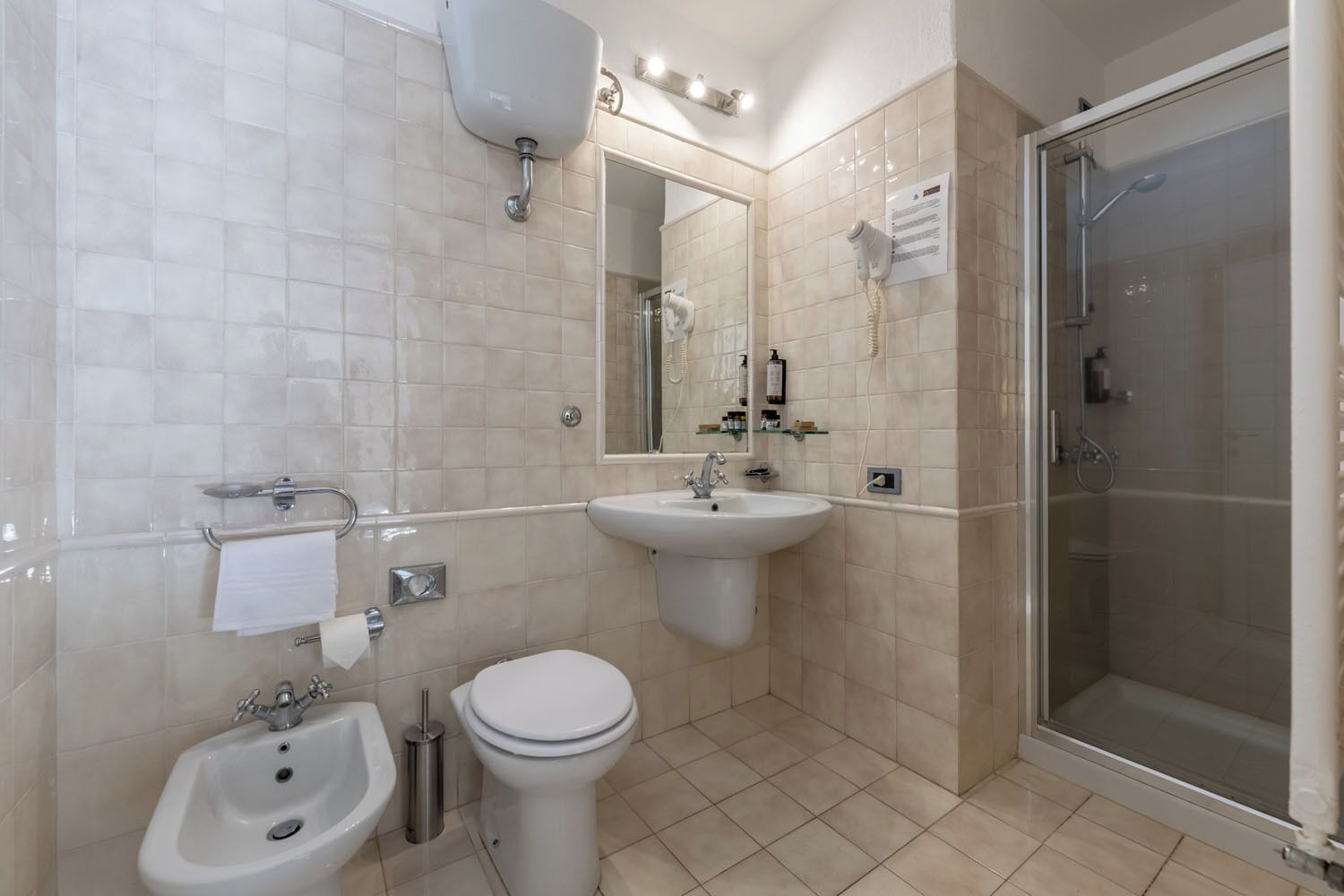 A modern bathroom with a sink, toilet, bidet, and a glass-enclosed shower.