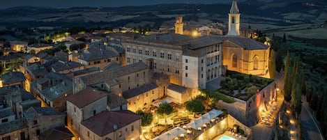 A historic town with a prominent church, a square with a pool, and a well-lit street.