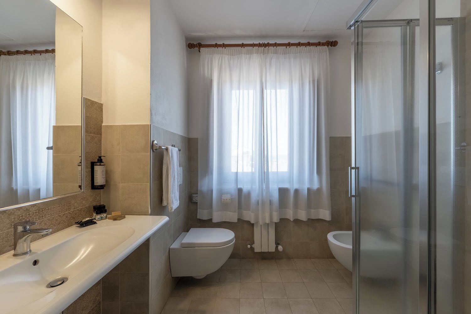 Baño con lavamanos doble, inodoro y zona de ducha.