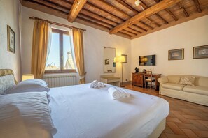 Habitación de hotel con una cama grande, un escritorio, un sofá y una ventana con cortinas.