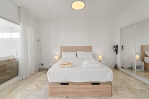 A hotel room with a bed, bedside lamps, a mirror, and a view of the outside. - RDR568 - Charming 1 Bed Apt in Jardines del Mar (Marbella)