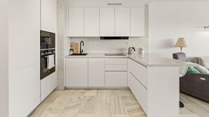 A modern kitchen with white cabinetry, a built-in oven, and a countertop with a kettle. - RDR568 - Charming 1 Bed Apt in Jardines del Mar (Marbella)