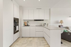 Eine moderne Küche mit weißen Schränken, einem eingebauten Backofen und einer Arbeitsplatte mit einem Wasserkocher.