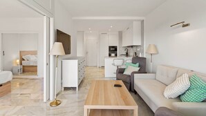A modern living room with a sofa, coffee table, and a view into the kitchen. - RDR568 - Charming 1 Bed Apt in Jardines del Mar (Marbella)