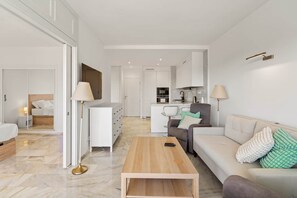Ein stilvolles Wohnzimmer mit einer Couch, einem Couchtisch und Blick in die Küche.