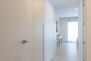 Ein moderner Hotelgang mit minimalistischem Design, der eine weiße Tür, eine lange Diele und einen Essbereich mit Tisch und Stühlen zeigt.