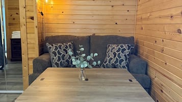 A wooden-paneled room with a sofa, a table with drawers, and a wall-mounted light fixture.