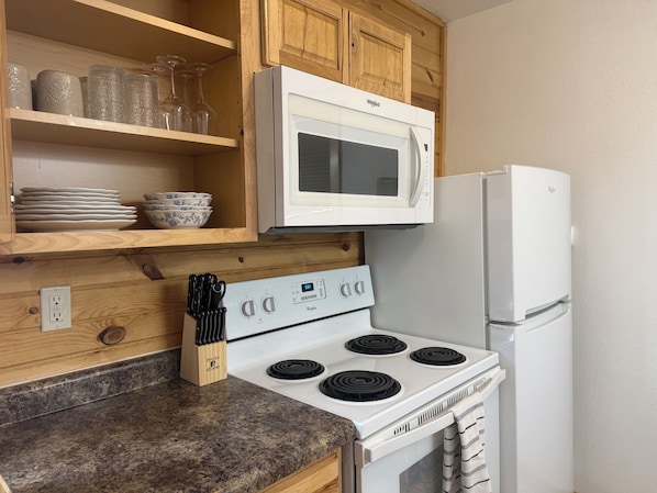 Una cocina con electrodomésticos blancos, armarios de madera y encimera de granito.
