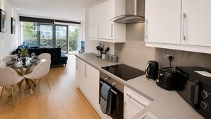 Eine moderne Küche mit weißen Schränken, einer schwarzen Induktionskochplatte und einer Kaffeemaschine.