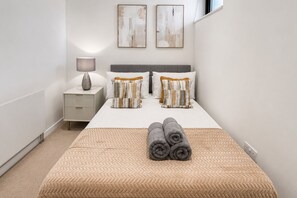 A neatly arranged bedroom with a bed, pillows, a bedside table, and a lamp. - Modern 2-Bedroom flat w/ AC & Balcony in Angel near King's Cros & Regent's Canal (London)