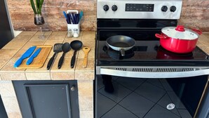 Une cuisine équipée d’une cuisinière, avec une casserole sur le feu et divers ustensiles de cuisine posés sur le plan de travail.