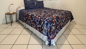 Une chambre à coucher comprenant un lit, une table de chevet, une fenêtre avec des stores et deux éléments de décoration murale.