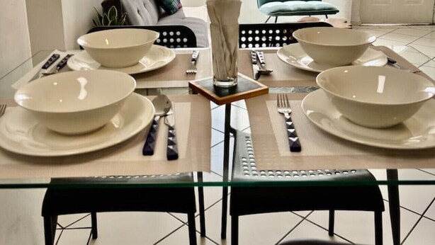 Un coin repas avec une table dressée pour quatre personnes, un canapé et une vue sur l’extérieur.