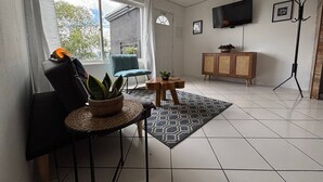 Un salon avec un canapé, une table à manger agrémentée d’une plante, un téléviseur et un meuble.