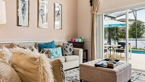 A living room with a sofa, ottoman, and a table with decorative items. There are three framed artworks on the wall. - 4 BDR South-Facing Disney Retreat (Kissimmee)
