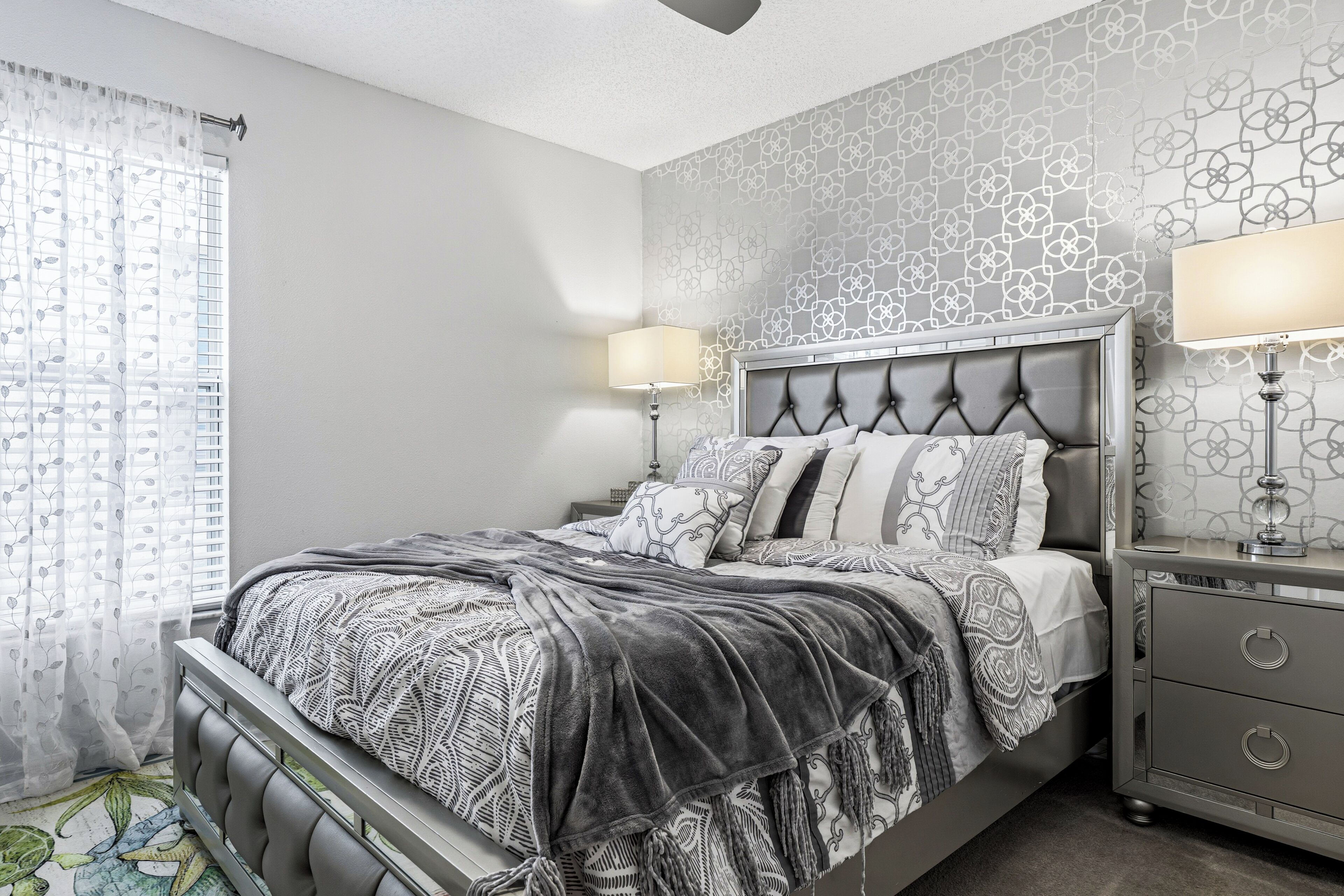 A bedroom with a bed, bedside tables, and a patterned wall.
