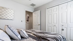 A bedroom with a bed, pillows, a wall art piece, and a door. - 4 BDR South-Facing Disney Retreat (Kissimmee)