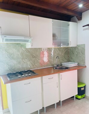 A compact kitchen with a gas stove, a sink, and white cabinets. - Margarita Penthouse Conil Center – Balcony & Air Conditioning (Conil de la Frontera)