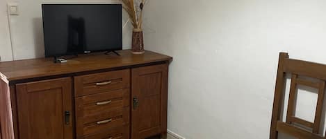 Une pièce avec un meuble en bois, une télévision, une chaise et une carte posée sur le sol.