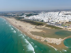 Luftaufnahme einer Küstenstadt mit Strand, Gebäuden und einem Yachthafen.
