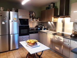 A kitchen with stainless steel appliances, a white countertop, and a table with a fruit bowl. - Provencal-style farmhouse with charm, swimming pool, and landscaped grounds on 6,200 m² (Draguignan)