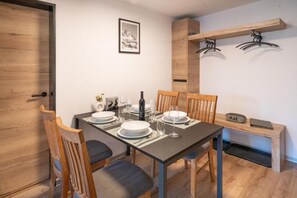 A dining area with a table set for four, chairs, a wooden bench, a coat rack, and a framed picture on the wall. - Apartment Bergliebe (Zermatt)